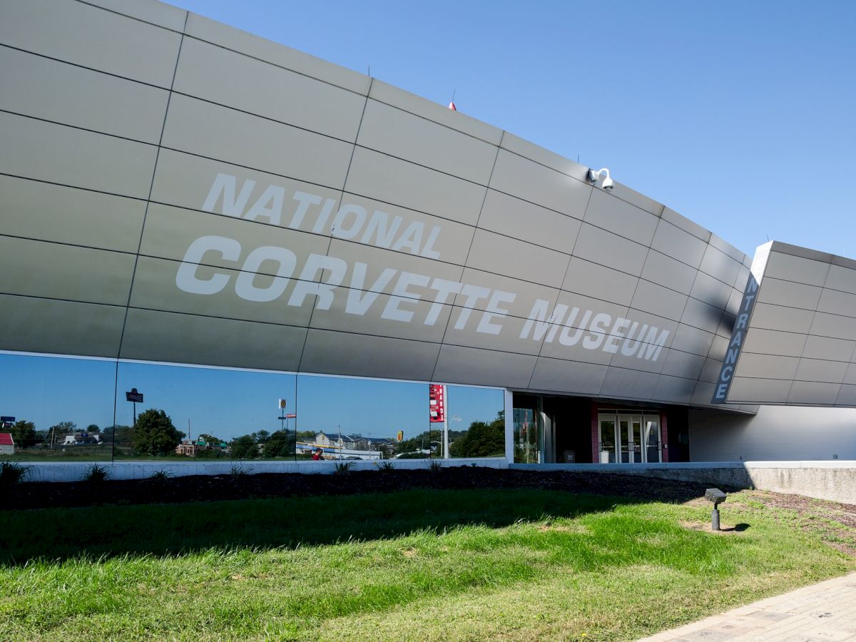 The image shows the exterior of the National Corvette Museum with its name prominently displayed on the building.