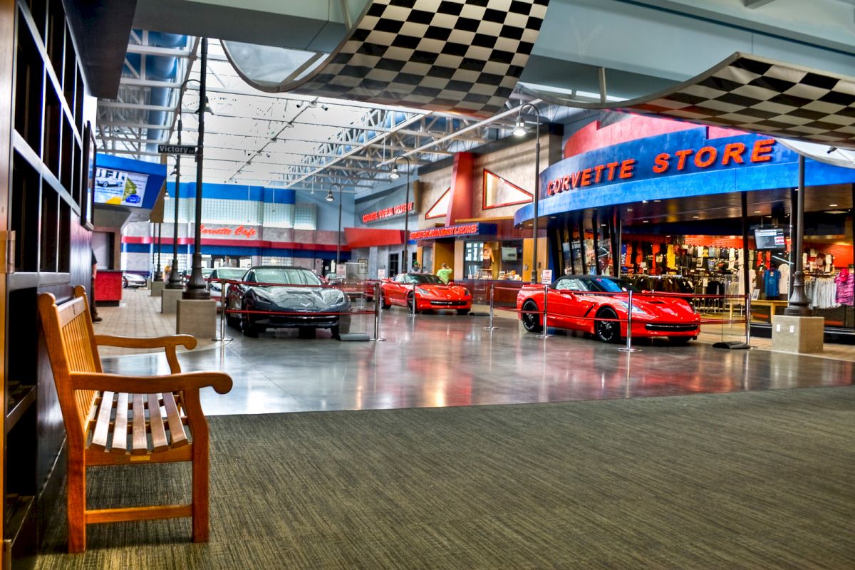 The image shows an indoor display with several sports cars, primarily red in color, and a store named 