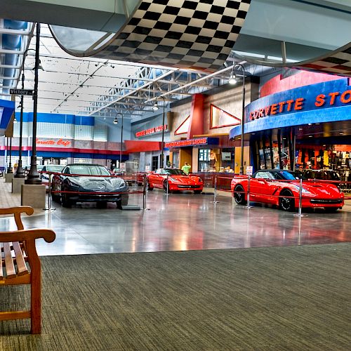 The image displays a showroom with red sports cars and a 