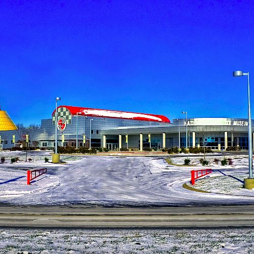 A building with a large yellow cone structure, surrounded by snow, and a modern facade with a red swoosh design on the roof.