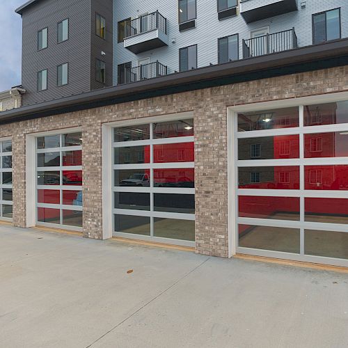 The image shows a building with four large glass garage doors, likely part of a commercial or residential complex.